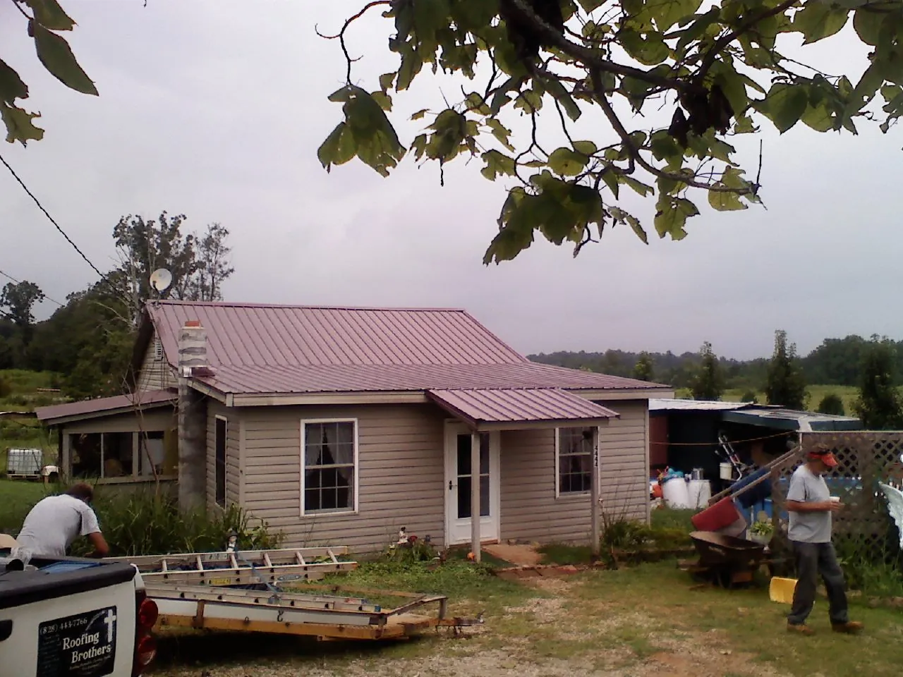 Crew finishing a mauve metal roof on a small farmhouse in Dyersburg