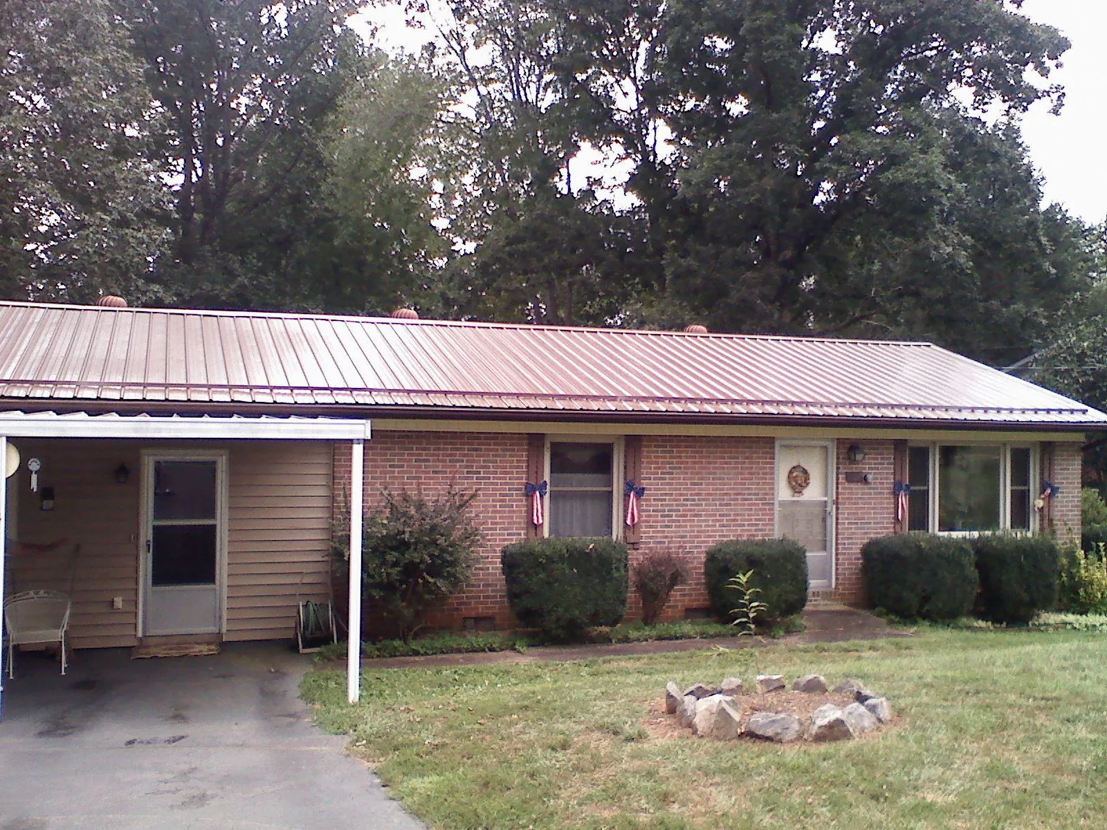 Bronze metal roof and carport on a brick ranch home — Roof Repair work by our crew in Dyersburg