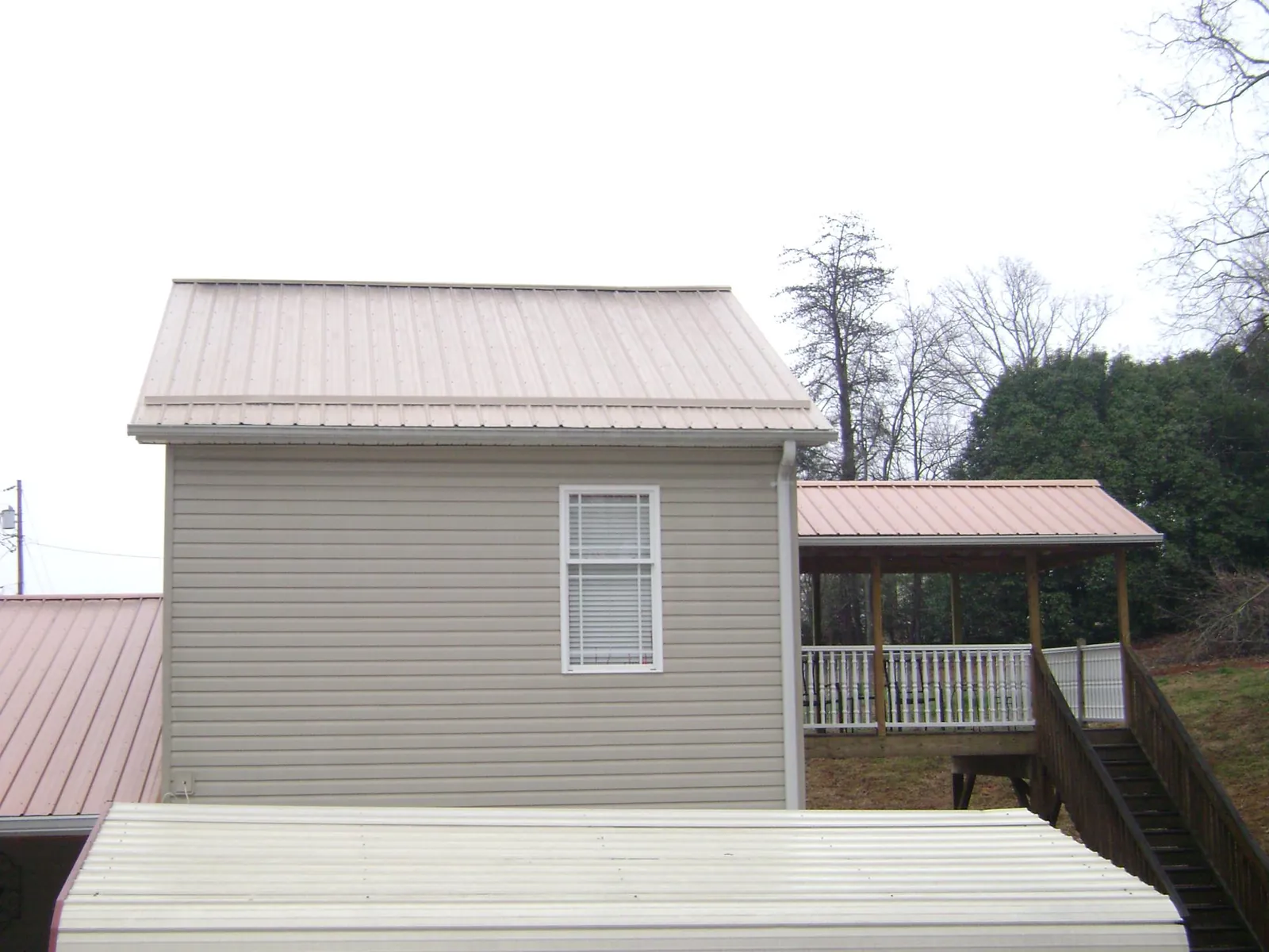 Tan metal roofs on a two story addition and attached porch, from a Roof Replacement job in Dyersburg