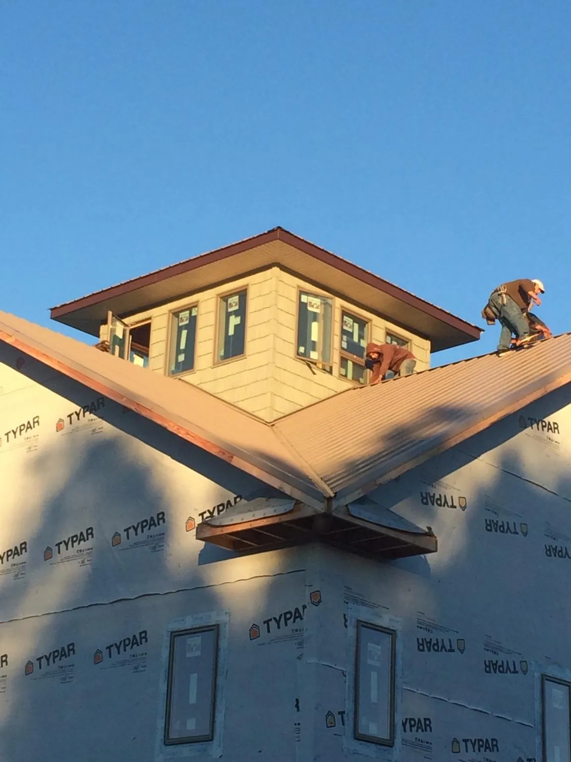 Roofers working around a rooftop cupola on a new metal roof at sunset — Roof Waterproofing in Dyersburg by Roofing Brothers